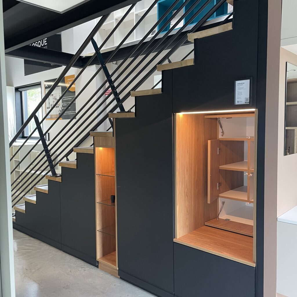 Optimisation d'espace pour ce sous escalier en mdf peint en noir et complété d'une niche ouverte qui sert d'assise et qui dissimule encore d'autres rangements.